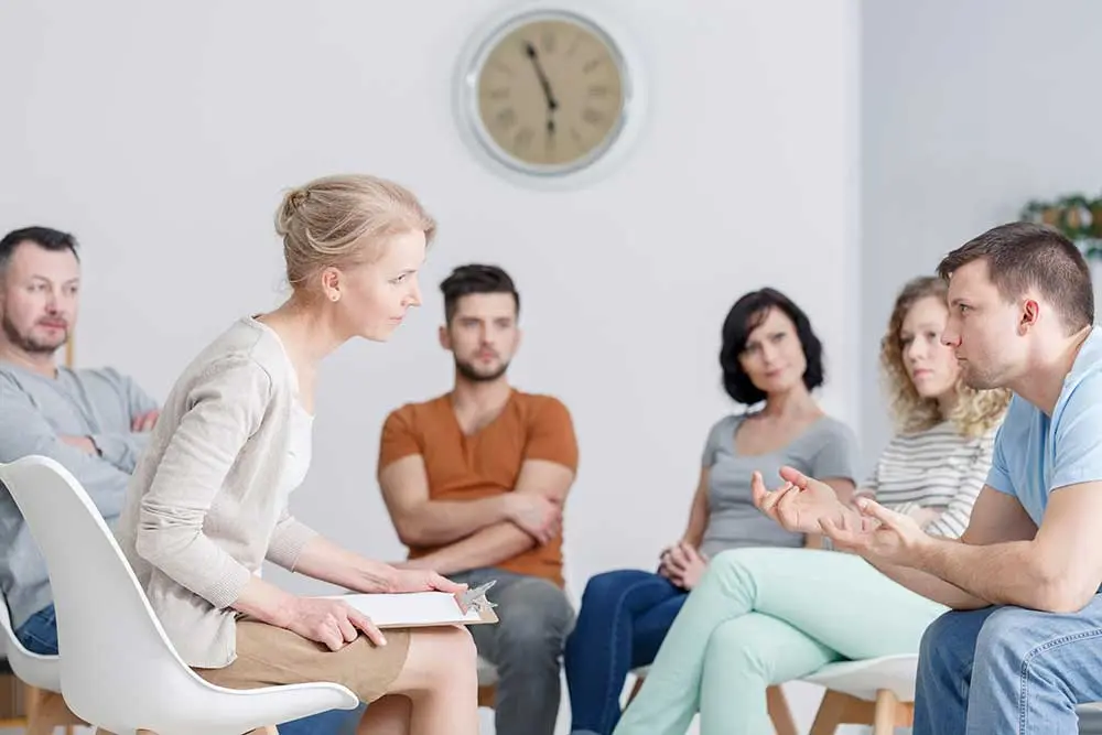 Diverse group of people sitting in circle in group therapy session. Diverse group of people sitting in circle in group therapy session.